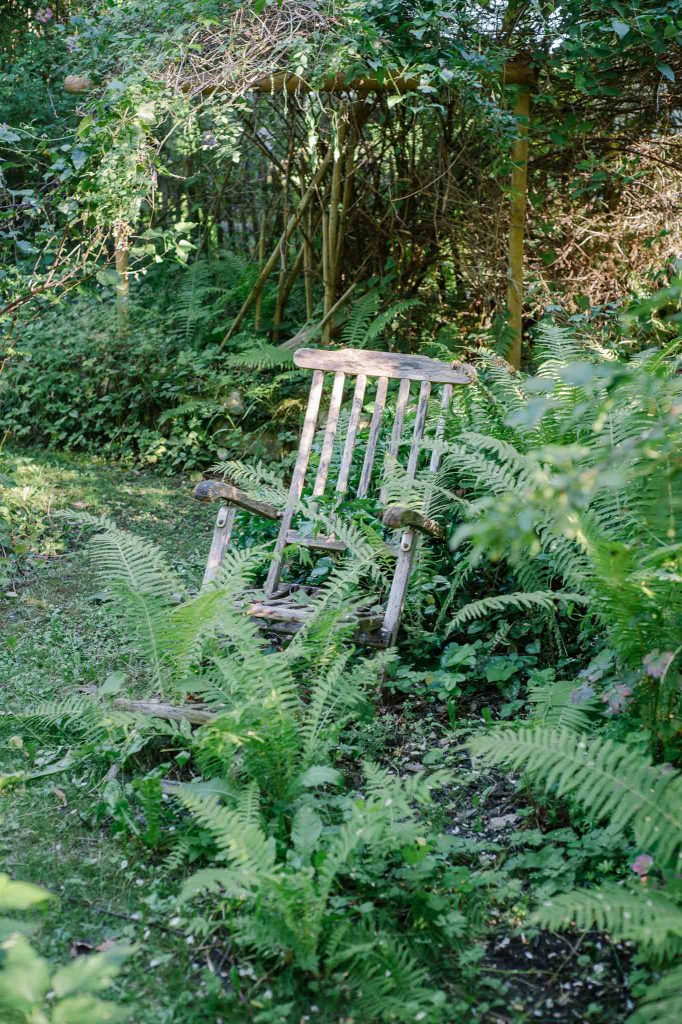 Wil-romantische Ecke im Schattengarten mit verwittertem Gartenstuhl und Farn