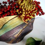 Chrysantheme und Hagebutten in einer länglichen Vase